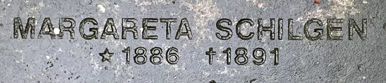 Nahaufnahme der eingemeißelten Inschrift „MARGARETA SCHILGEN ★1886 †1891“ auf einer Sammelgrabplatte des geräumten Friedhofs Heidberge